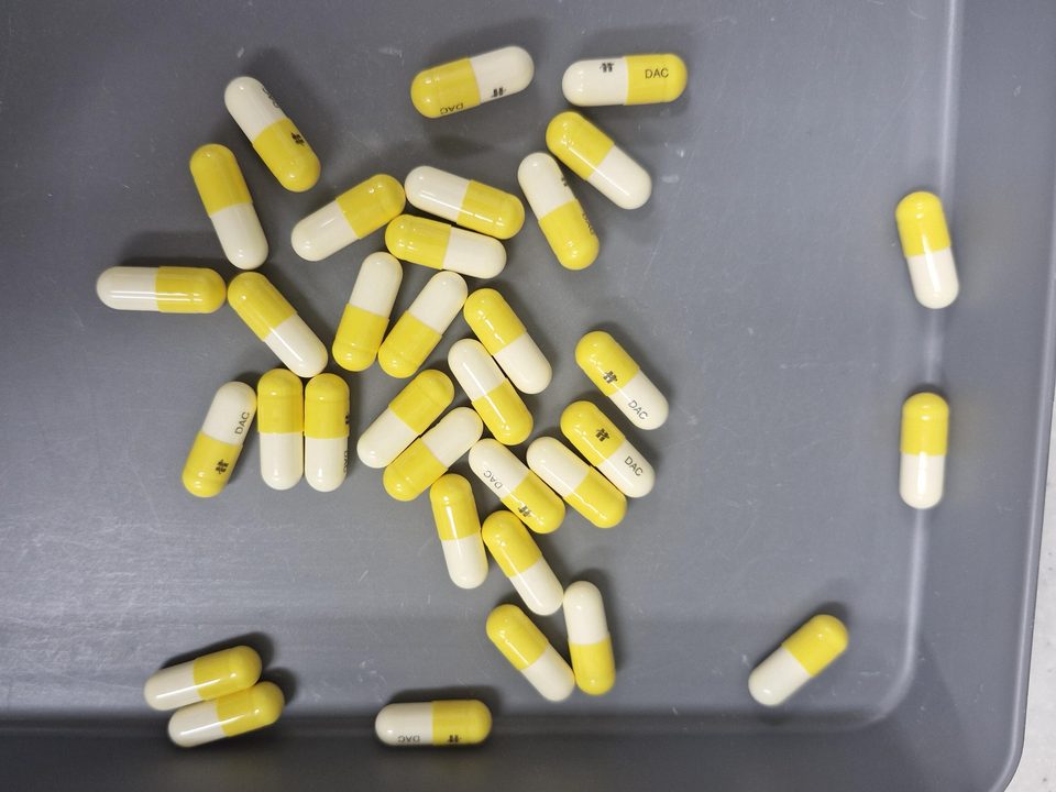 34 yellow and white capsules on a grey tray, each outlined and numbered.